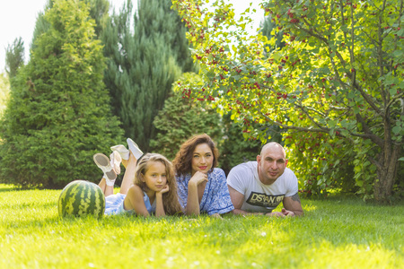 Young family with kids having picnic outdoors. Parents with two children relax in a sunny summer garden. Mother, father, little girl and baby boy eat sandwich and fruit, drink juice for lunch in parkの写真素材