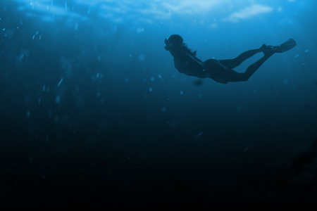 A girl in pointe shoes and a long dress is walking on the bottom of the oceanの写真素材