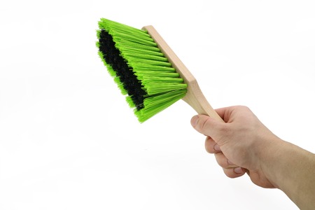 hand is holding a green dust broom isolated on white backgroundの写真素材