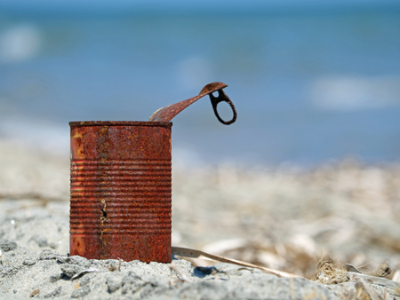 Rusty tin can on the beach with blue sea