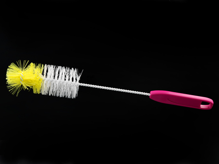 white and yellow bottle brush with pink handle isolated on black background
