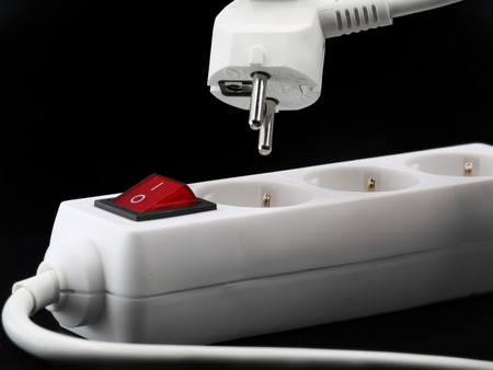 close up of power button and plug from a white power strip on black background