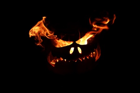 halloween pumpkin with flames from eyes on dark background