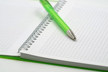 green spiral notebook with focus to ballpoint pen and copy spaceの写真素材