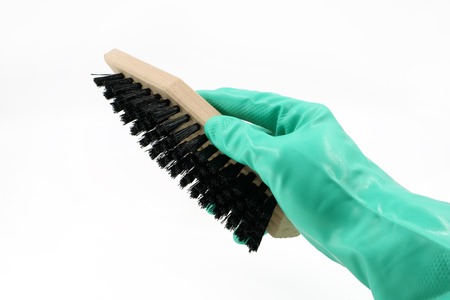 hand with glove is holding a shoe brush isolated on white backgroundの写真素材