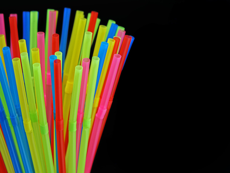 close up od different colored plastic drinking straws isolated on black