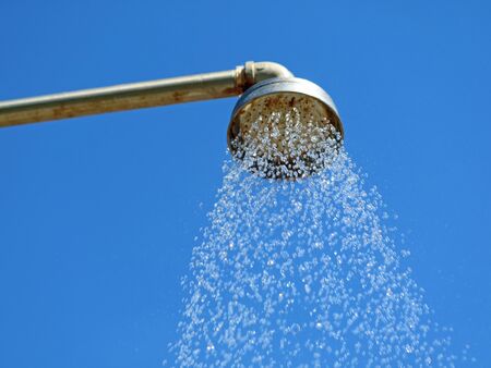Close up outdoor shower head with water drops on blue sky background