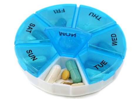 close up of round pill box with Mondays pills visible on white backgroundの写真素材