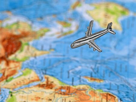 silver miniature airplane above blurred map on backgroundの写真素材