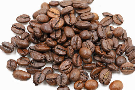 Roasted coffee beans heap isolated on white background, close up