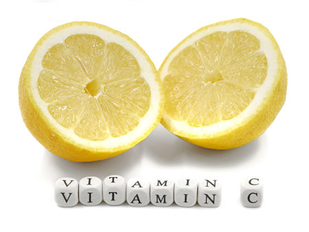 Fresh sliced ripe lemon with VITAMIN C word made from mini letter cubes isolated on white backgroundの写真素材