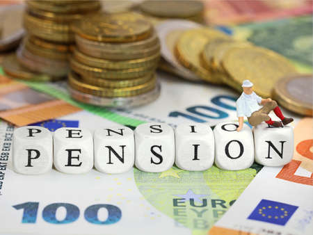 wooden letter cubes form the word PENSION on euro money background with banknotes and coins