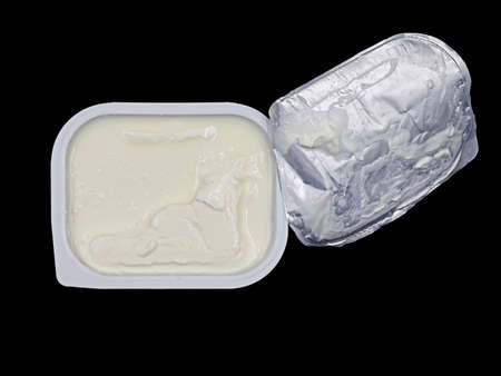 top view of quark or cream cheese in white plastic container isolated on black backgroundの写真素材
