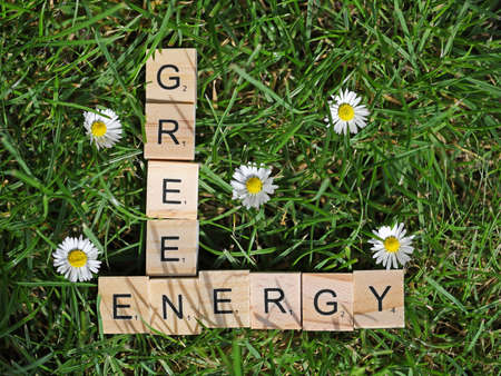 top view of the words green energy, written with wooden blocks in the grass between daisies, eco conceptの写真素材