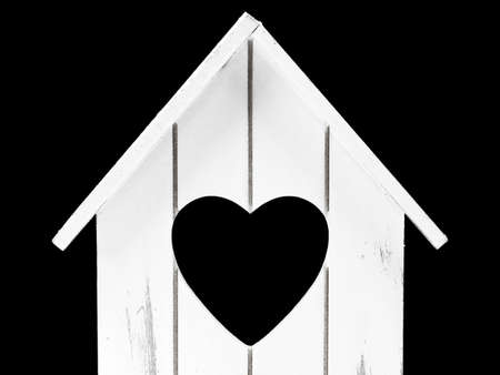 front view of miniatur wooden house with heart shape inside isolated on black background, concept of sweet home with copy spaceの写真素材