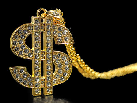 golden necklace dollar symbol with sparkling diamonds isolated on black background, close upの写真素材