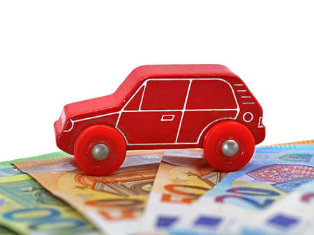 red wooden toy car on euro money banknotes isolated on white background with copy spaceの写真素材