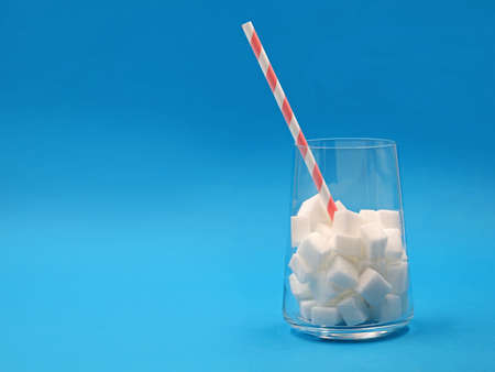 glass with sugar cubes and paper straw isolated on blue background with copy spaceの写真素材