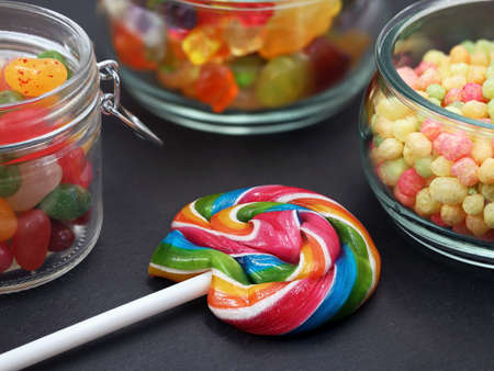 colorful lollipop and various sweets in jar on black background, close upの写真素材