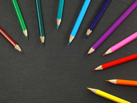 top view of colored pencils isolated on black slate background with copy spaceの写真素材