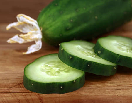 Close-up of cut cucumber slices of an outdoor cucumber with dried fruit blossom, freshly harvested home-grown vegetablesの写真素材