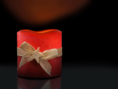 burning red christmas candle with jute band and star on black background, illuminated christmas decorationの写真素材