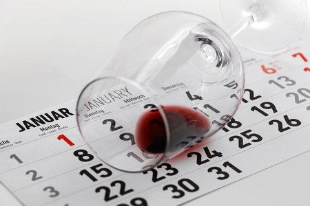 Overturned wine glass with leftover wine on January calendar sheet, concept image for the Dry January Challenge, a New Years resolution to stop drinking for a monthの写真素材