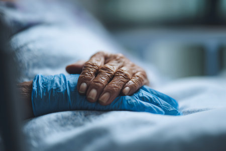 Close-up of hands of an elderly woman lying in a hospital bedの素材