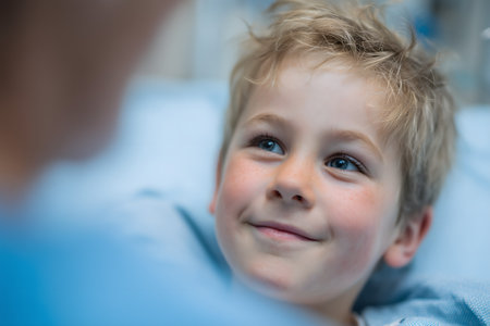 Close-up portrait of smiling little boy lying on bed in hospital wardの素材