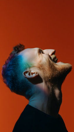 Funny portrait of young man with colorful hair and beard on orange backgroundの素材