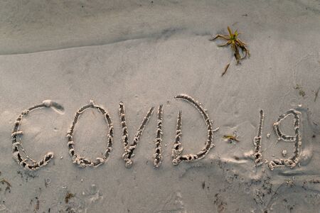 inscription covid-19 on the sand at the beach