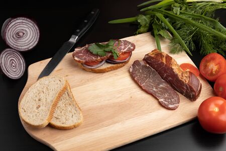 The finished sandwich on the kitchen board with different ingredientsの写真素材