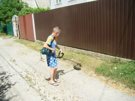 Baby mows grass with hand-electro lawnmowerの写真素材