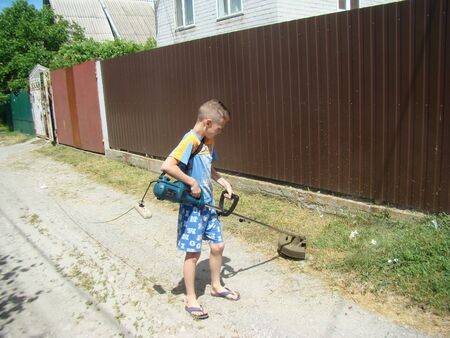 Baby mows grass with hand-electro lawnmowerの写真素材
