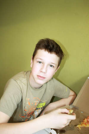 baby boy eats pizza sitting at the table