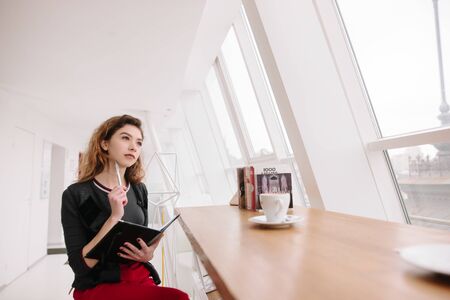 The girl thought. She sits in a cafe with a notebookの写真素材