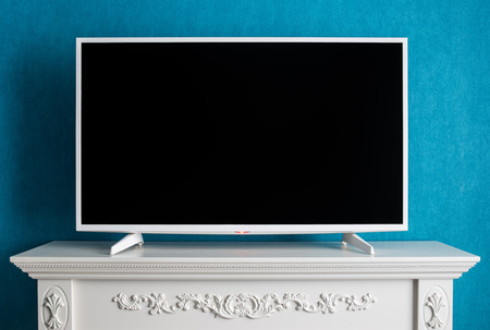 The white modern TV with the empty black screen. The TV costs on a curbstone with patterns on a background a wall with wall-paper of color of a sea waveの写真素材