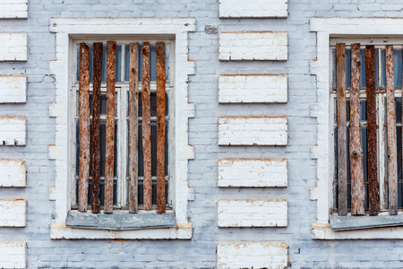 Part of the facade of the old brick building with boarded up windows.の写真素材