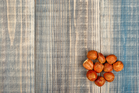 A pile of peeled hazelnuts lies on a wooden background