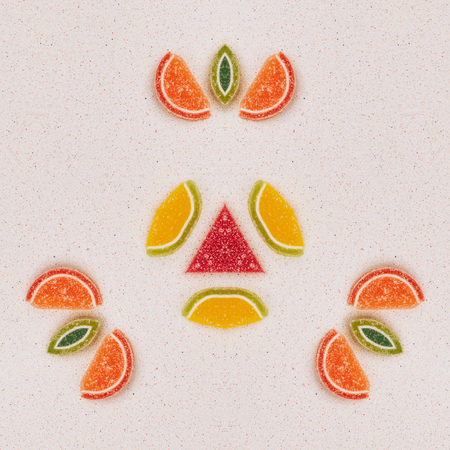 Mandala made from fruit made from marmalade. The pattern is on the gray table top. View from above
