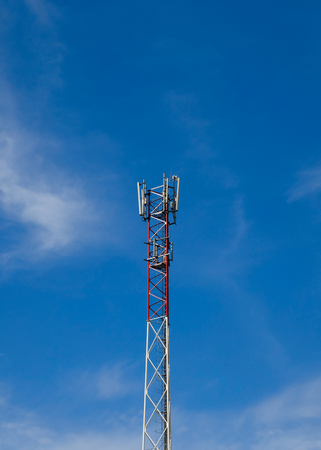 A part of the cell phone tower against a blue sky with clouds