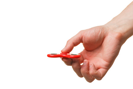 Male hand holding a red fidget spinner isolated on white backgroundの写真素材