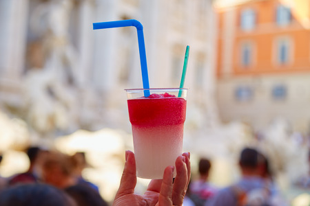 Two-colored ice dessert granita in hand in the background Trevi fountainの写真素材