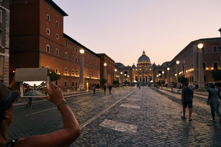 ROME - AUGUST 4: Tourist is taking photos with phone of St. Peter's Cathedral during the dusk with illumination on August 4, 2017 in Rome Italyのeditorial素材
