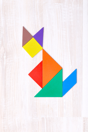 Flay lay of colorful tangram figures arranged in shape of cat on wooden table.の写真素材