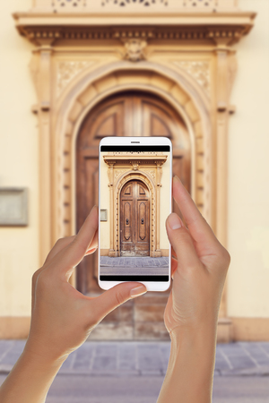 A tourist is taking a photo of old wooden door in Florence, Italy on a mobile phoneの写真素材