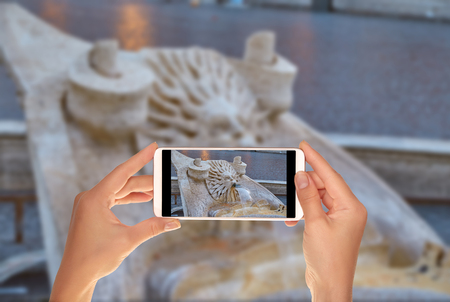 A tourist is taking a photo of detail of the fountain in the Piazza of Spagna near the Spanish Steps in Rome on a mobile phoneの写真素材
