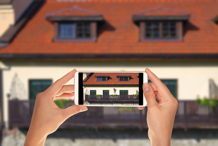 A tourist is taking a photo of balcony with flowers in the old town of Vilnius, Lithuania on a...