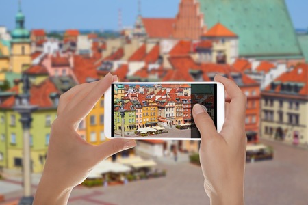 A man is making a photo of main square of the old town in Warsaw, Poland without people on a mobile phoneの写真素材
