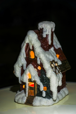 Macro picture of a small candle Christmas winter house with black backgroundの写真素材